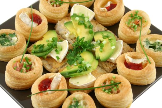 Assorted vol au vonts and avocado and camembert bites on a platter.