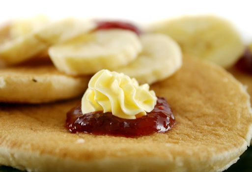 Delicious pancakes with butter swirls and strawberry jam with banana.