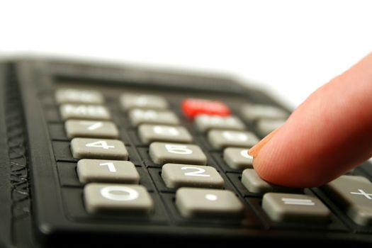 Close up of fingertip on the the keyboard of a calculator.
