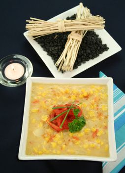 Roasted capsicum chili and corn chowder in a dark blue table setting.