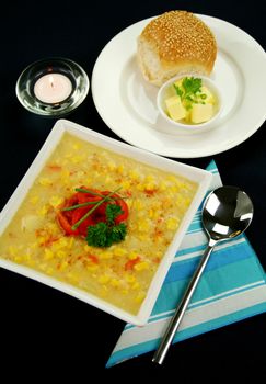 Roasted capsicum chili and corn chowder in a dark blue table setting.