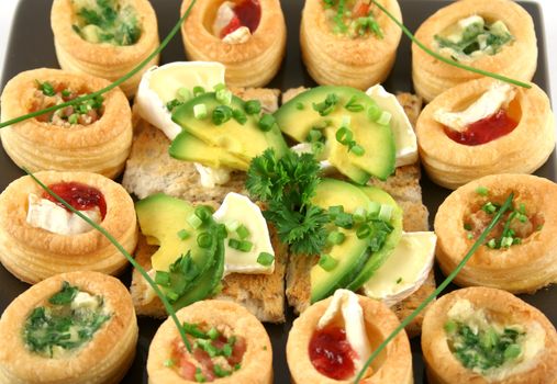 Assorted vol au vonts and avocado and camembert bites on a platter.