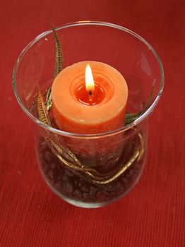 Decorative candle with gold leaf in a glass candle holder with stones.