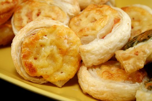 Baked cheese and ham scrolls amongst assorted savory pastries.