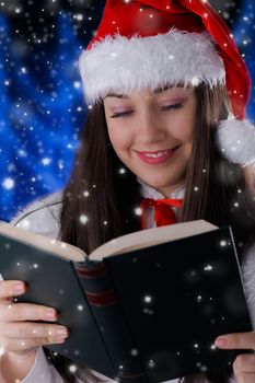 Beautiful girl holding a hard cover book or album with snow falling around her.