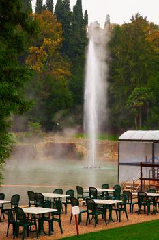 Green tables and chairs near a thermal lake 