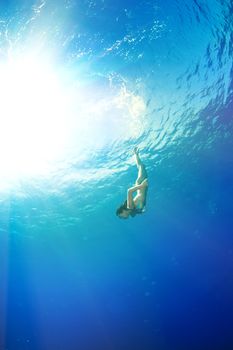 athletic girl diving under the sea