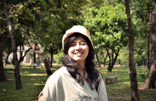 Portrait of beautiful smiling young woman in yellow hat, against background of summer green park, Sepia toned