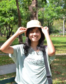 Portrait of beautiful smiling woman in yellow hat, against background of summer green park