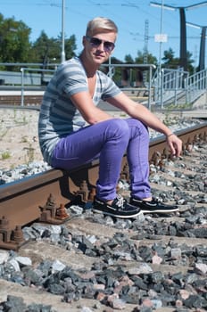 Shot of one man sitting on train tracks