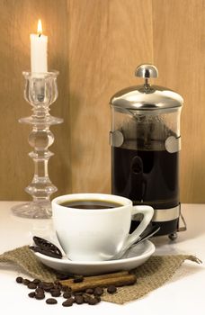 cup of coffee, chocolate and cinnamon on a napkin from a rough fabric and french press