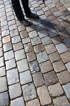 Man with umbrella and his shadow on old cobblestoned street in Nuremberg, Germany.