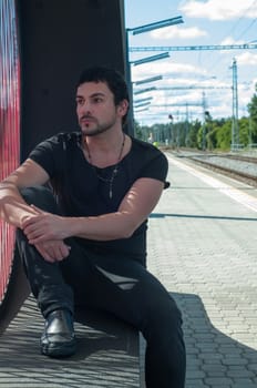 Shot of handsome man in black sitting on platform