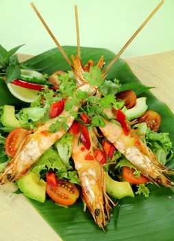 Delicious Asian chilli shrimp skewers a salad on a banana leaf.