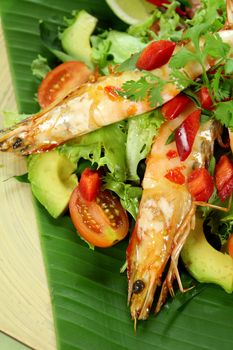 Delicious Asian chilli shrimp skewers a salad on a banana leaf.