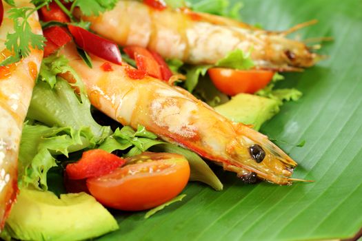 Delicious Asian chilli shrimp skewers a salad on a banana leaf.