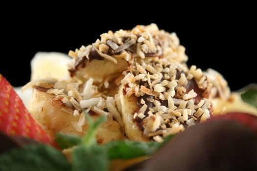 Pancake topped with chocolate and coconut coated bananas with strawberries and kiwi fruit.