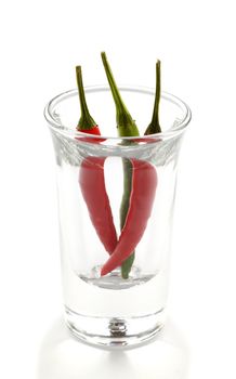 Three red and green hot chillies in a shot glass.