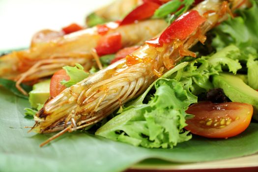 Delicious Asian chilli shrimp skewers a salad on a banana leaf.