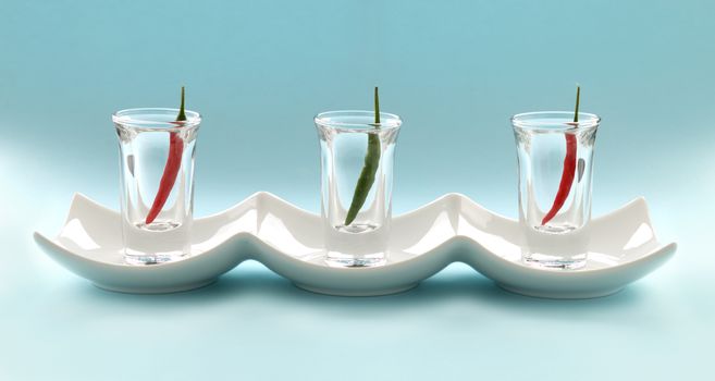 A row of red and green hot chillies lined up in shot glasses.