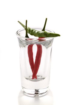 Three red and green hot chillies in a shot glass.