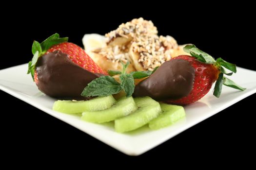 Pancake topped with chocolate and coconut coated bananas with strawberries and kiwi fruit.