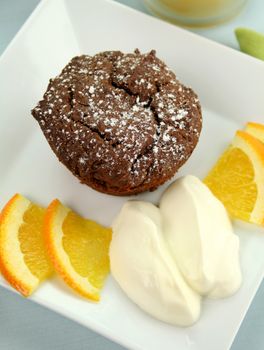 Chocolate brownie with orange and whipped cream ready to serve.