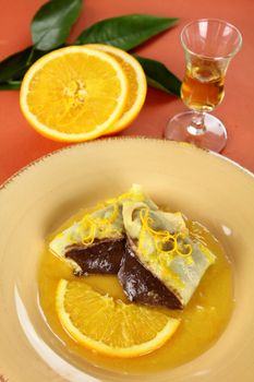 Sliced chocolate crepe suzette with orange sauce and a slice of orange.