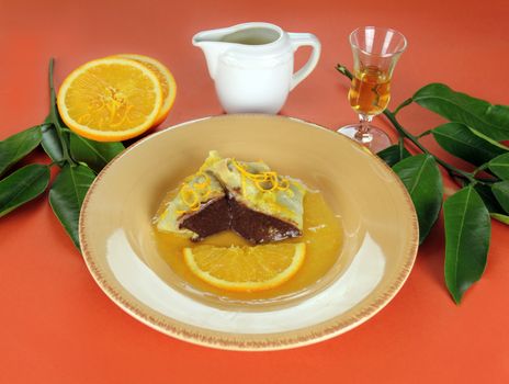Sliced chocolate crepe suzette with orange sauce and a slice of orange.