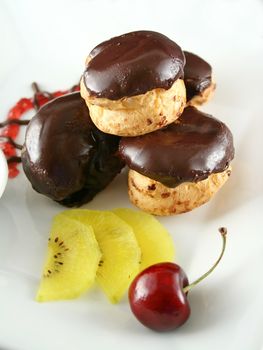 Chocolate profiteroles with kiwi fruit and a cherry.