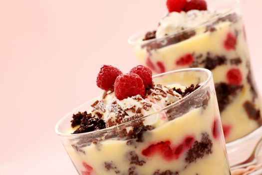 Delicious chocolate trifle dessert served in two glasses topped with raspberries.