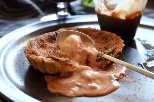 Beautiful fresh baked chocolate tart with melted caramel ice cream.