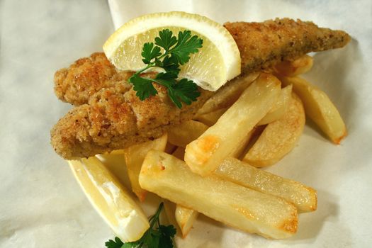 Classic fish and chips meal of crumbed whiting fillet with chips in paper.