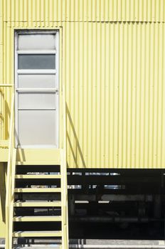 Yellow industrial stairs and galvanized iron wall