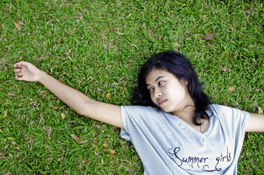 Young asian woman laying in the green grass