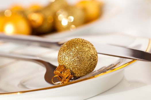 silver cutlery decorated with a golden Christmas bauble