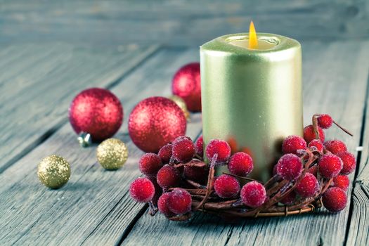 Christmas wreath from red berries with a candle on wooden background