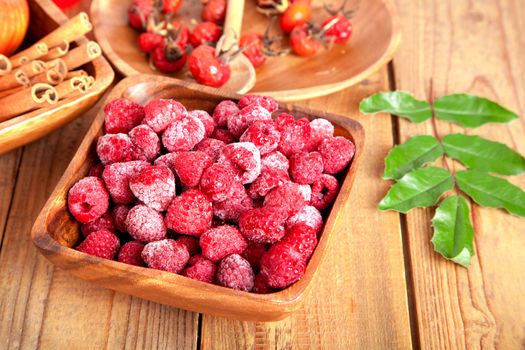 frozen raspberries in the wooden bowl with spoon.