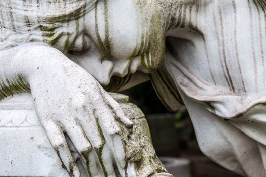 detail of a mourning sculpture on a cemetery