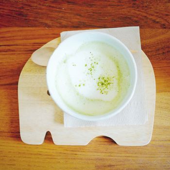 Matcha green tea latte on wooden tray with retro filter effect