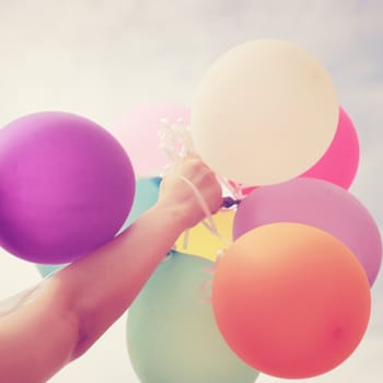 Hand holding multicolored balloons with retro filter effect