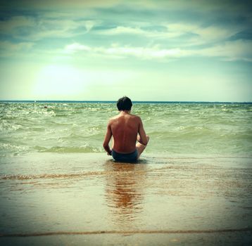 Vintage photo of person sitting on the brink of sea