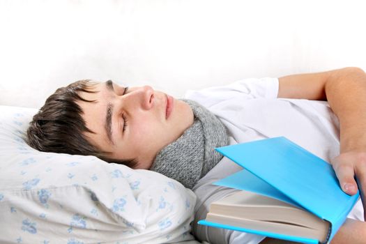 Tired Young Man Sleeps with a Book on the bed