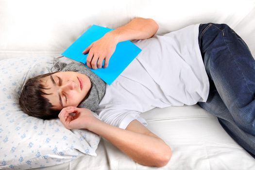 Tired Young Man Sleeps with a Book on the bed