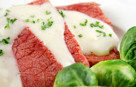 Delicious sliced corn beef with white sauce and vegetables.