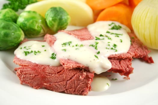 Delicious sliced corn beef with white sauce and vegetables.