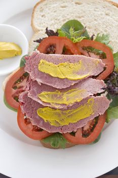 Delicious open corned beef open sandwich with mustard and fresh garden salad.