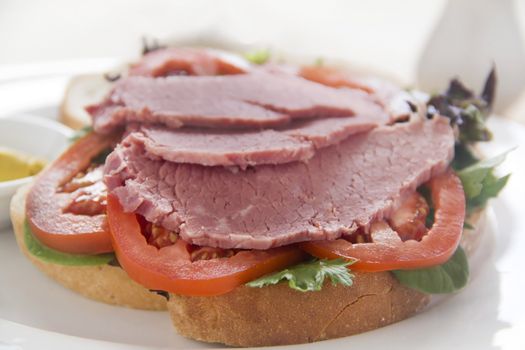 Delicious corned beef open sandwich with mustard and fresh garden salad.