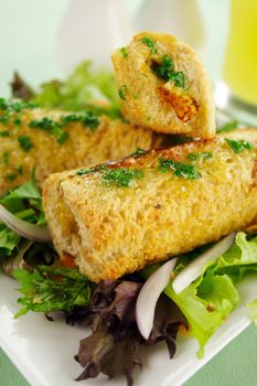 Vegetarian baked corn rolls dripping with parsley butter on a bed of mixed lettuce.