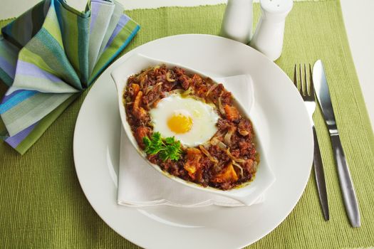 Baked corned beef hash with egg, tomato and onion with parsley.